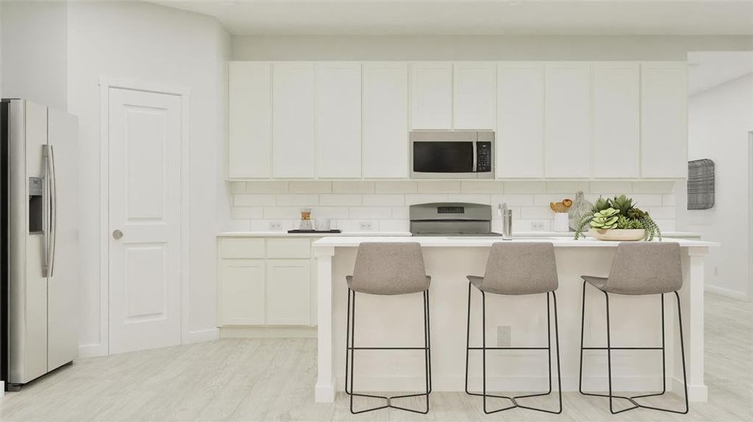 Kitchen featuring stainless steel appliances, tasteful backsplash, a kitchen island with sink, a breakfast bar, and white cabinetry Kitchen featuring stainless steel appliances, tasteful backsplash, a kitchen island with sink, a breakfast bar, and white cabinetry