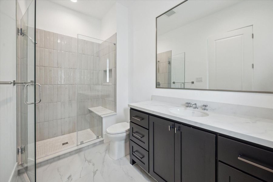 En-suite bath features glass-enclosed freestanding shower lined with Maniscalco Contour glossy tiles, Quartz countertops, and large vanity area with under-cabinet storage. En-suite bath features glass-enclosed freestanding shower lined with Maniscalco Contour glossy tiles, Quartz countertops, and large vanity area with under-cabinet storage.