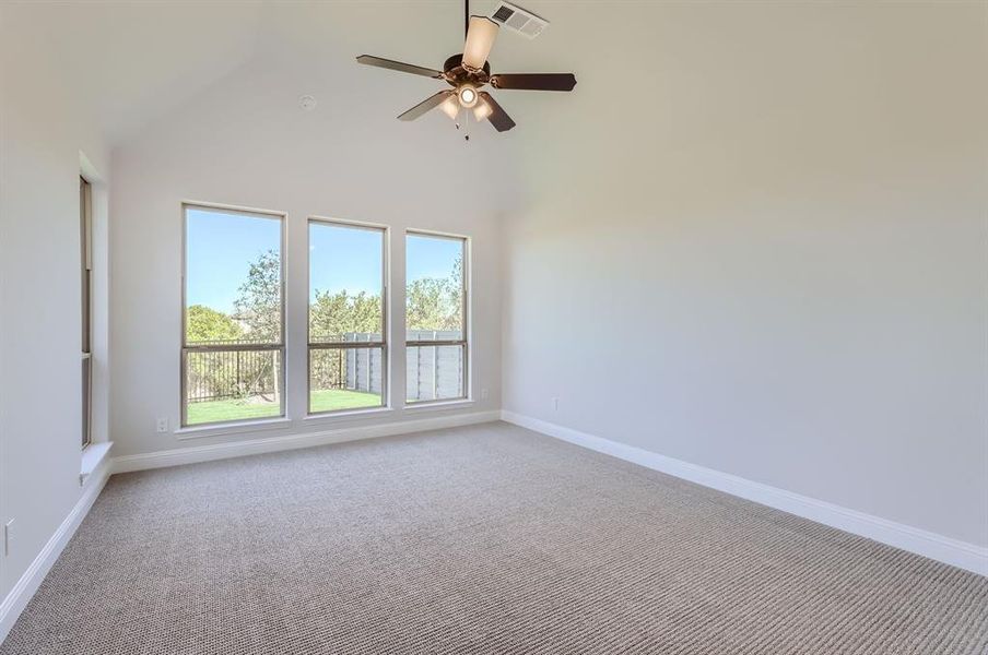 Carpeted spare room featuring high vaulted ceiling and ceiling fan