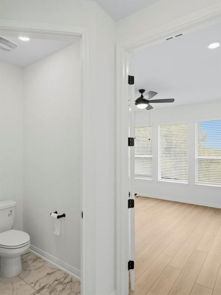 A glimpse into a versatile room with light wood flooring, perfect for various living arrangements, adjoined by a convenient half-bath. A glimpse into a versatile room with light wood flooring, perfect for various living arrangements, adjoined by a convenient half-bath.