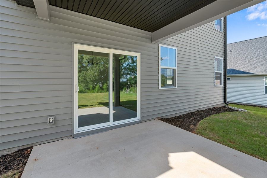 Sliding glass doors open onto a concrete patio ove