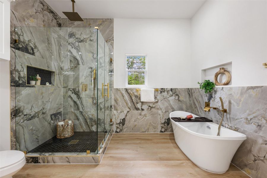 Bathroom with a freestanding bath, a marble finish shower, tile walls, and a wainscoted wall Bathroom with a freestanding bath, a marble finish shower, tile walls, and a wainscoted wall