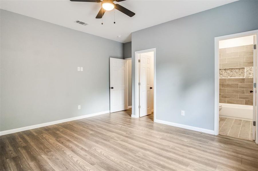 Unfurnished bedroom featuring ensuite bathroom, hardwood / wood-style flooring, and ceiling fan