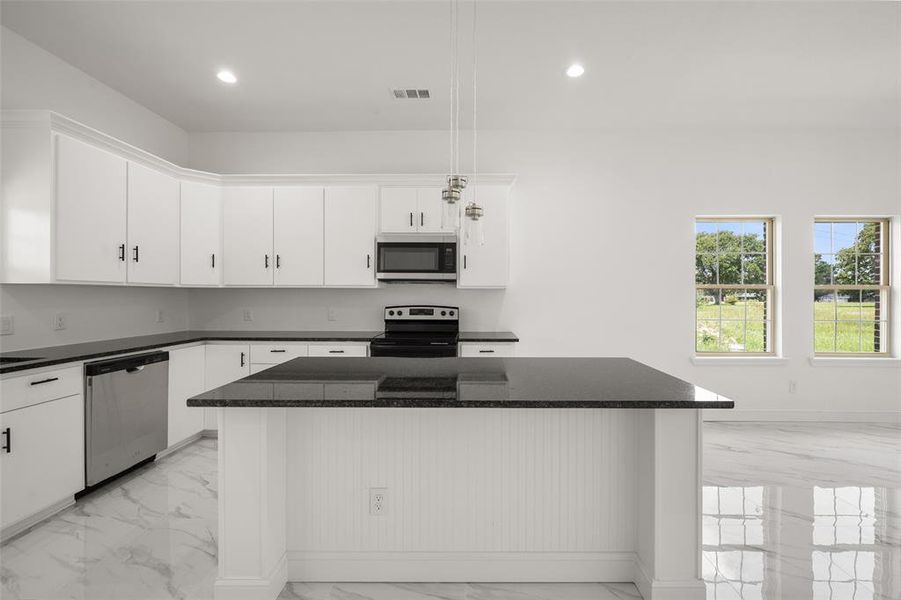 Kitchen featuring stainless steel appliances, light marble finish flooring, recessed lighting, white cabinets, and a kitchen island Kitchen featuring stainless steel appliances, light marble finish flooring, recessed lighting, white cabinets, and a kitchen island