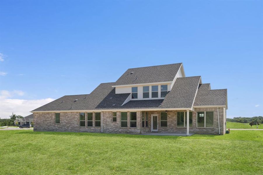 Back of property with brick siding, roof with shingles, a yard, and a patio Back of property with brick siding, roof with shingles, a yard, and a patio