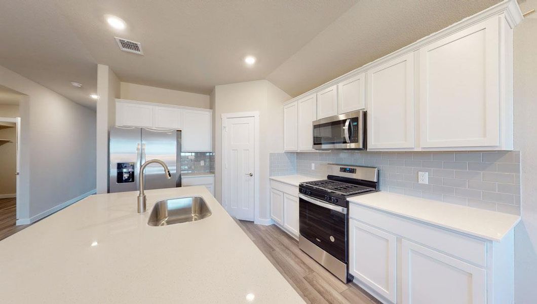 Kitchen with stainless steel appliances, white cabinets, backsplash, light wood-type flooring, and recessed lighting