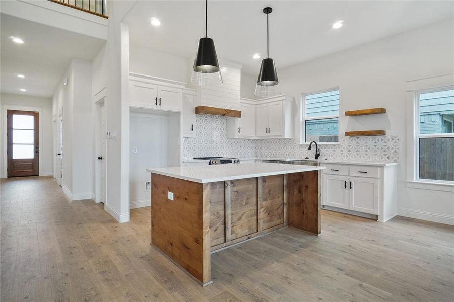 Kitchen featuring white cabinetry, a center island, open shelves, backsplash, and recessed lighting