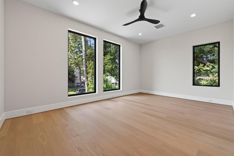 Additional flexible living space with ceiling fan and large windows for natural light.