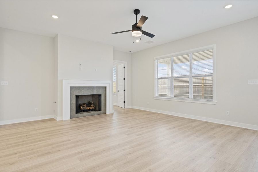 Spacious living area featuring light wood-finish flooring, a contemporary ceiling fan, and recessed lighting Spacious living area featuring light wood-finish flooring, a contemporary ceiling fan, and recessed lighting