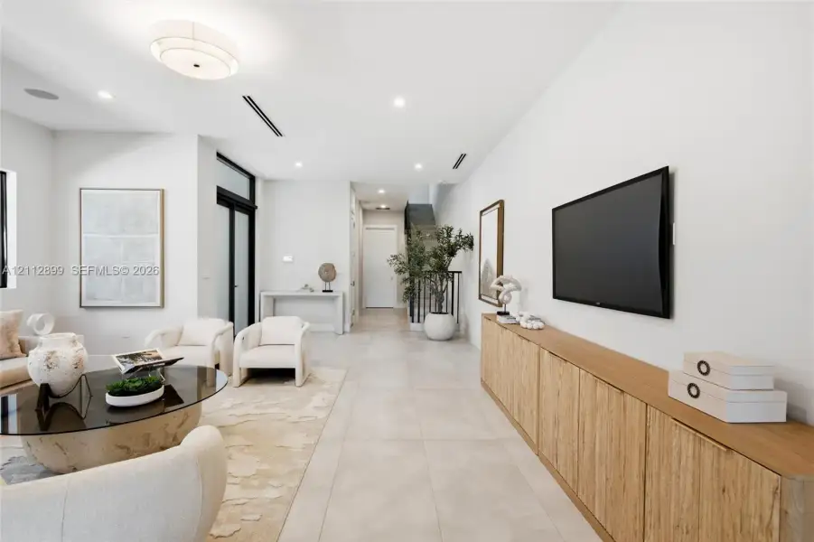 Large-format tile flooring, built-in wooden cabinetry, recessed lighting, and a multi-tiered drum light fixture