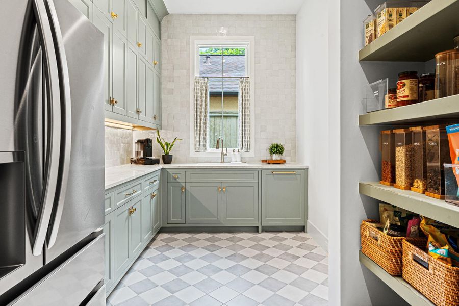 A thoughtfully designed extension of the main kitchen, the scullery kitchen offers both function & elevated style. Taj Mahal quartzite countertops pair w/ a Zellige tile backsplash, while open pantry shelving & abundant cabinetry provide exceptional storage. Complete w/ an oversized sink, secondary Bosch dishwasher & space for a second refrigerator, designed for seamless everyday use. A thoughtfully designed extension of the main kitchen, the scullery kitchen offers both function & elevated style. Taj Mahal quartzite countertops pair w/ a Zellige tile backsplash, while open pantry shelving & abundant cabinetry provide exceptional storage. Complete w/ an oversized sink, secondary Bosch dishwasher & space for a second refrigerator, designed for seamless everyday use.