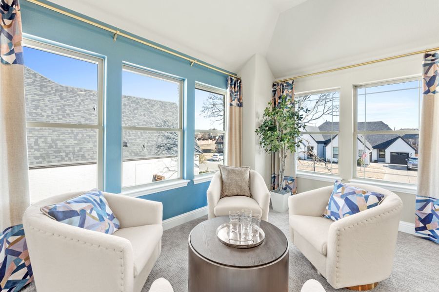 Bright sitting room with three white armchairs, round coffee table, and large windows with blue accent wall Bright sitting room with three white armchairs, round coffee table, and large windows with blue accent wall