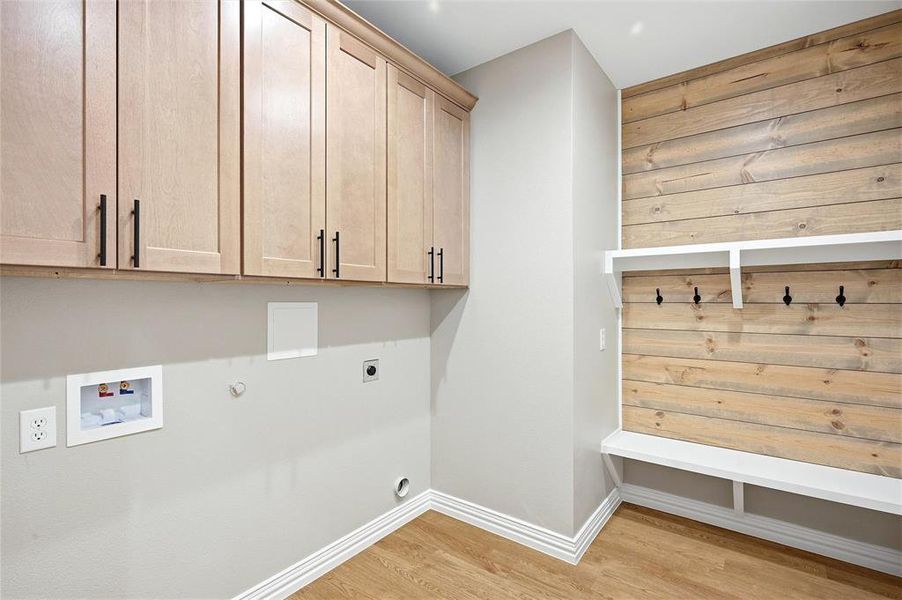 Laundry area featuring gas dryer hookup, light wood finished floors, hookup for an electric dryer, cabinet space, and hookup for a washing machine Laundry area featuring gas dryer hookup, light wood finished floors, hookup for an electric dryer, cabinet space, and hookup for a washing machine