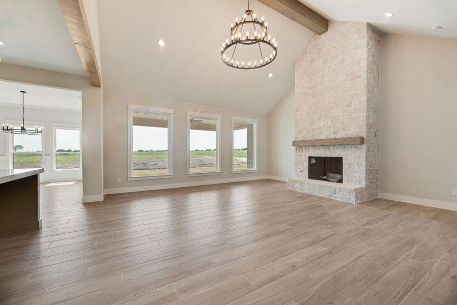 Unfurnished living room with a chandelier, beamed ceiling, light wood-style flooring, a fireplace, and recessed lighting Unfurnished living room with a chandelier, beamed ceiling, light wood-style flooring, a fireplace, and recessed lighting
