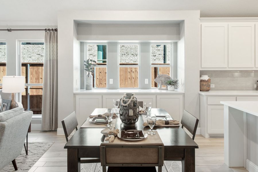 Dining area with dark wood table, built-in window nook, and open view to white kitchen cabinets