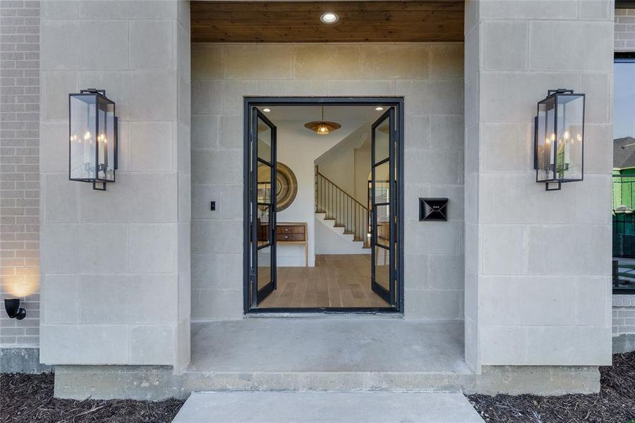 Grand entry featuring a stone facade with brick accents and double iron-framed glass doors