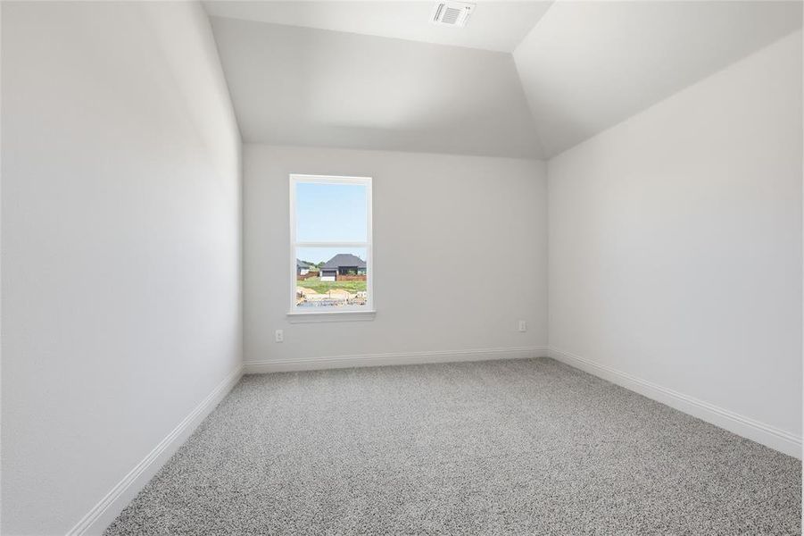 Unfurnished room featuring light carpet and vaulted ceiling