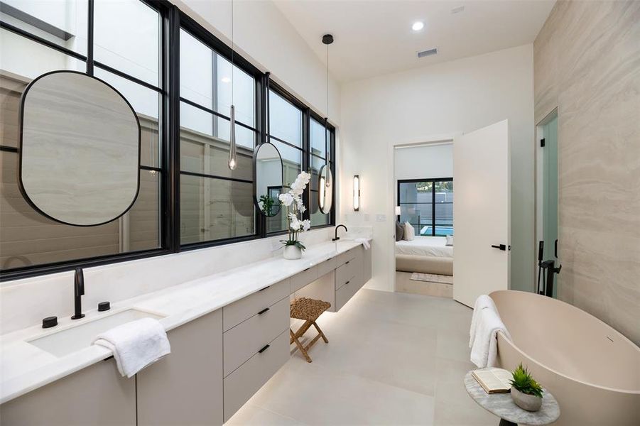 Full bath featuring double vanity, a freestanding tub, ensuite bathroom, and recessed lighting