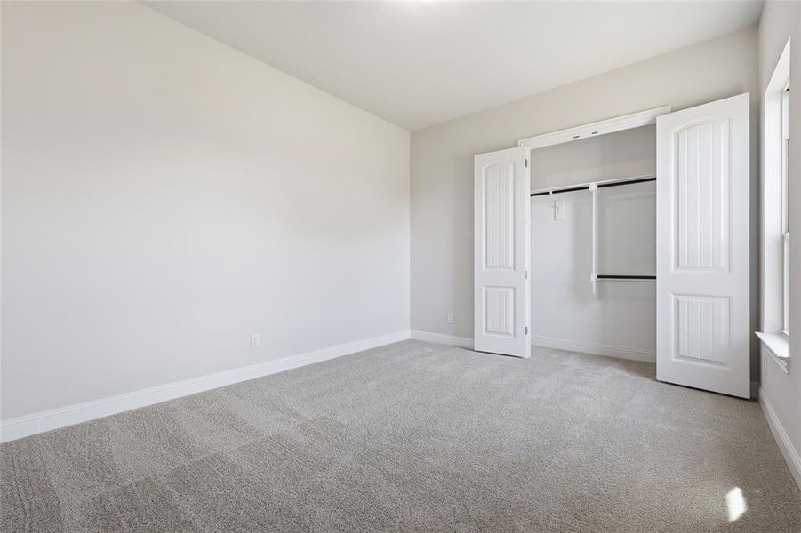 Unfurnished bedroom with light colored carpet and a closet Unfurnished bedroom with light colored carpet and a closet