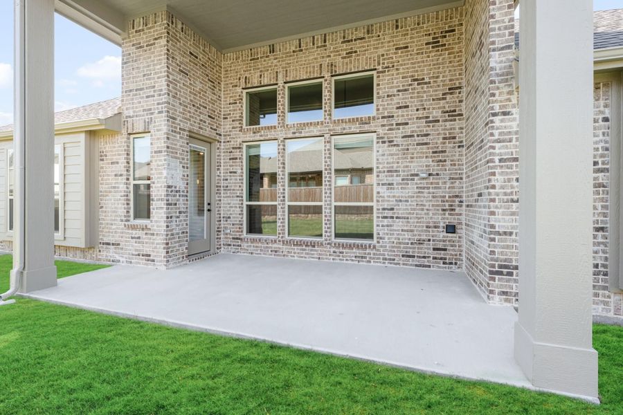 Covered back patio with concrete slab, brick exterior, and green lawn Covered back patio with concrete slab, brick exterior, and green lawn