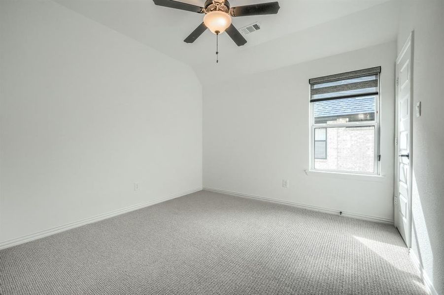 Empty room with visible vents, baseboards, carpet, and a ceiling fan