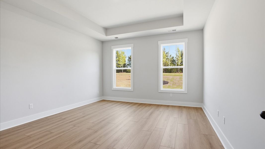 Serene and stylish primary bedroom featuring hardwood flooring and a thoughtful, modern layout at Benjamin's Grove Serene and stylish primary bedroom featuring hardwood flooring and a thoughtful, modern layout at Benjamin's Grove