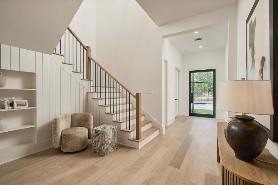 An intimate sitting area creates a natural pause between spaces, while the open staircase adds architectural interest and a sense of connection throughout the home.