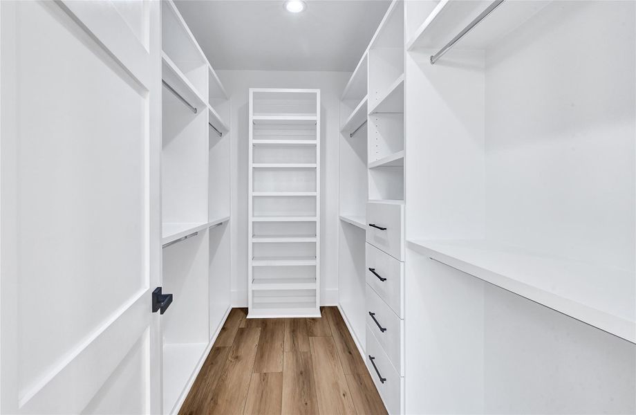 Oversized walk-in closet with custom built-ins, ample hanging space, shelving, and storage drawers.