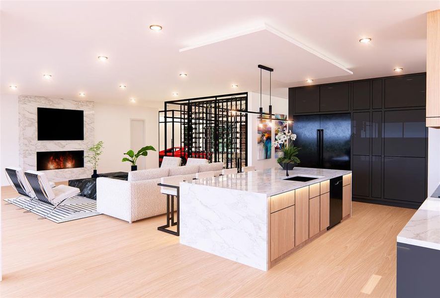 Kitchen with light brown cabinets, an island with sink, light hardwood / wood-style flooring, a premium fireplace, and light stone countertops