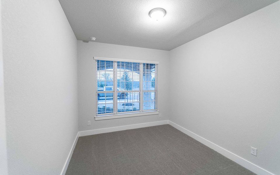 Empty room with baseboards, dark carpet, and a textured ceiling