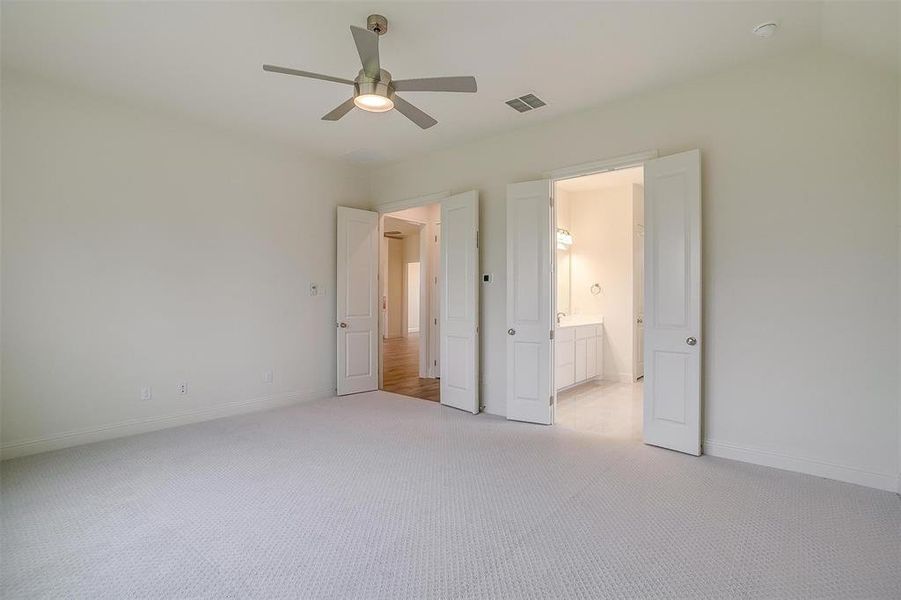 Unfurnished bedroom featuring ceiling fan, light carpet, and vaulted ceiling