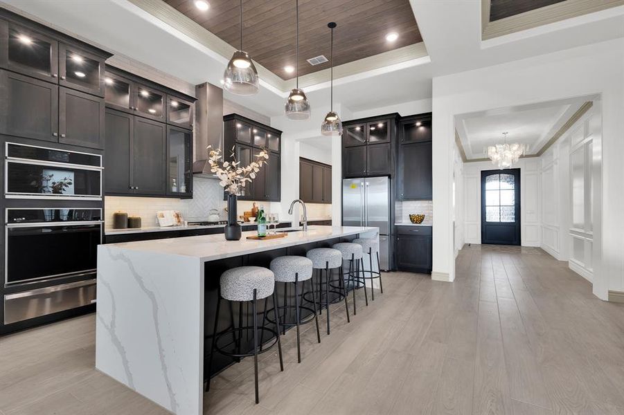 Kitchen featuring a kitchen bar, decorative backsplash, dark cabinetry, hanging light fixtures, and wooden ceiling
