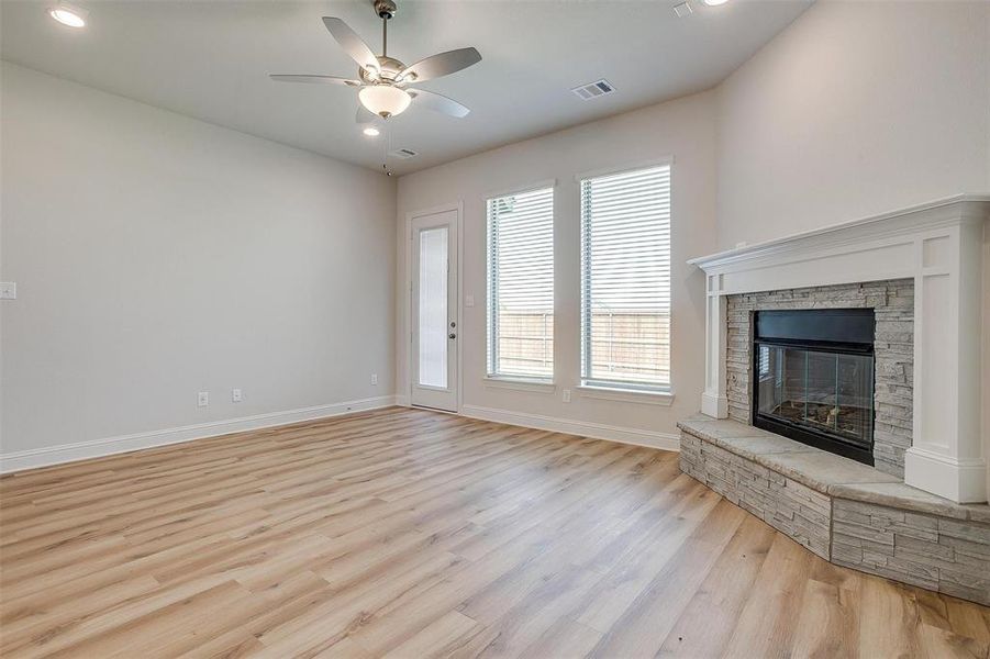 Unfurnished living room with a fireplace, ceiling fan, and light hardwood / wood-style floors