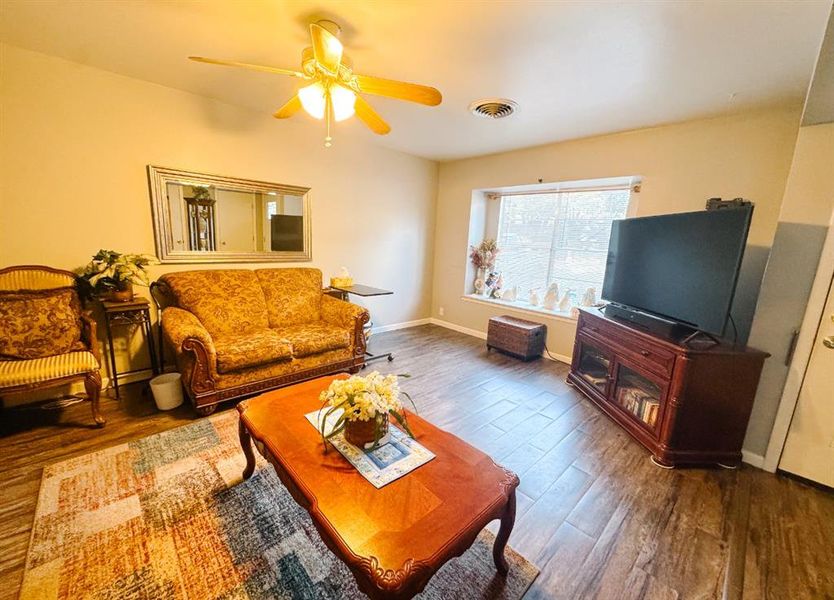 Living area featuring dark wood-type flooring and a ceiling fan