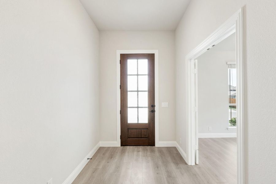 Entryway with dark wood front door featuring glass panels and light gray hardwood floors Entryway with dark wood front door featuring glass panels and light gray hardwood floors