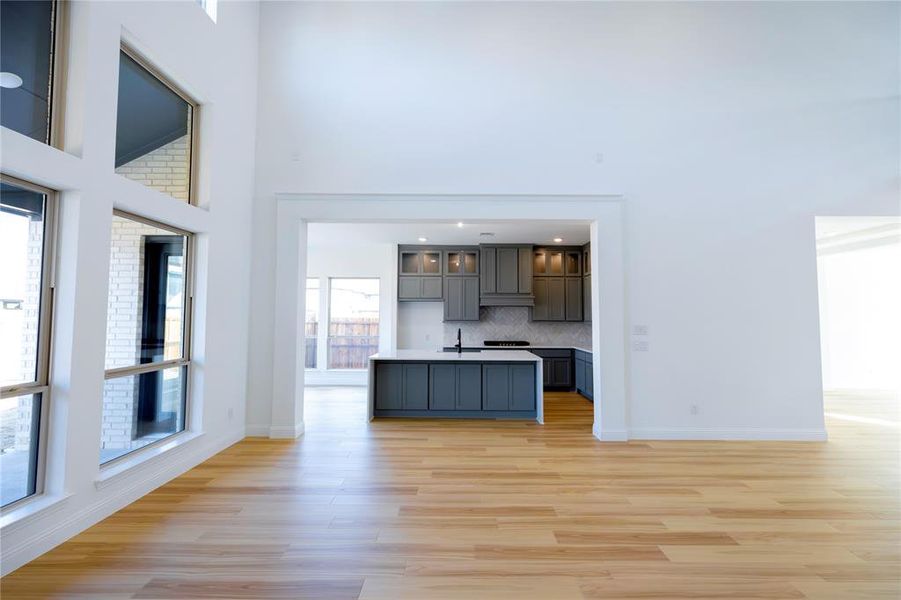 Kitchen featuring glass insert cabinets, open floor plan, plenty of natural light, an island with sink, and a towering ceiling Kitchen featuring glass insert cabinets, open floor plan, plenty of natural light, an island with sink, and a towering ceiling