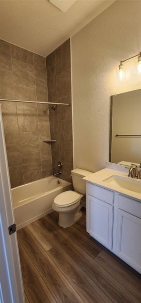 Full bathroom featuring wood finished floors, vanity, bathtub / shower combination, a textured wall, and a textured ceiling Full bathroom featuring wood finished floors, vanity, bathtub / shower combination, a textured wall, and a textured ceiling