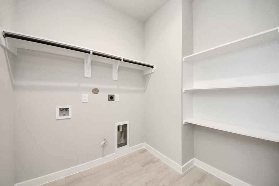 A perfect blend of functionality and comfort. Capture the essence of easy living with a first-floor laundry room, thoughtfully equipped with shelving for effortless organization. Both electric and gas connections available. Sample photo of completed home with similar floor plan. Actual colors and selections may vary. A perfect blend of functionality and comfort. Capture the essence of easy living with a first-floor laundry room, thoughtfully equipped with shelving for effortless organization. Both electric and gas connections available. Sample photo of completed home with similar floor plan. Actual colors and selections may vary.