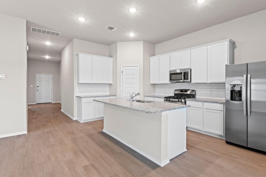 This super efficient, well-designed kitchen features white cabinetry, granite countertops, a tile backsplash, and a pantry This super efficient, well-designed kitchen features white cabinetry, granite countertops, a tile backsplash, and a pantry