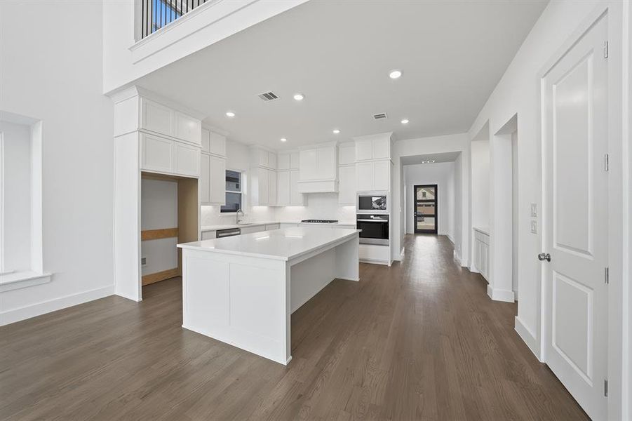 Kitchen with white cabinetry, a center island, oven, dark wood-style flooring, and recessed lighting Kitchen with white cabinetry, a center island, oven, dark wood-style flooring, and recessed lighting