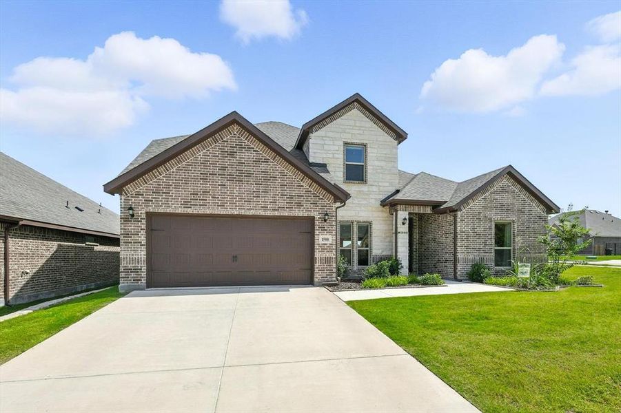 French country style house featuring an attached garage, driveway, brick siding, a front lawn, and stone siding