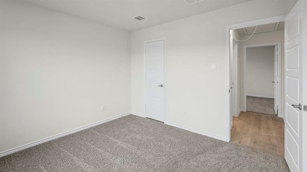 Unfurnished bedroom featuring attic access, carpet flooring, visible vents, and baseboards
