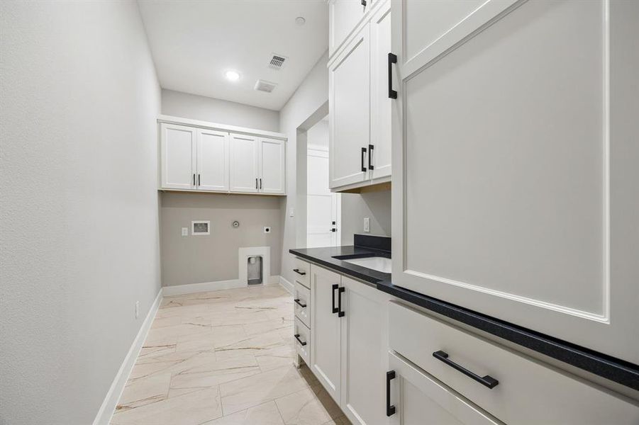 Laundry area featuring gas dryer hookup, light marble finish floors, cabinet space, hookup for an electric dryer, and washer hookup Laundry area featuring gas dryer hookup, light marble finish floors, cabinet space, hookup for an electric dryer, and washer hookup