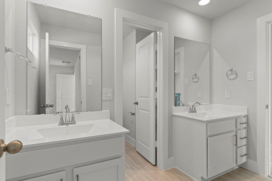 The secondary bathroom offers modern convenience with a sleek vanity, full mirror, and bright lighting. The adjoining layout provides easy access for upstairs bedrooms while maintaining privacy and style.