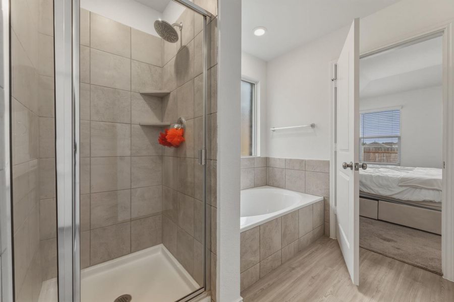 The bathroom features a tiled shower with a glass enclosure and built-in shelving, alongside a tiled corner bathtub
