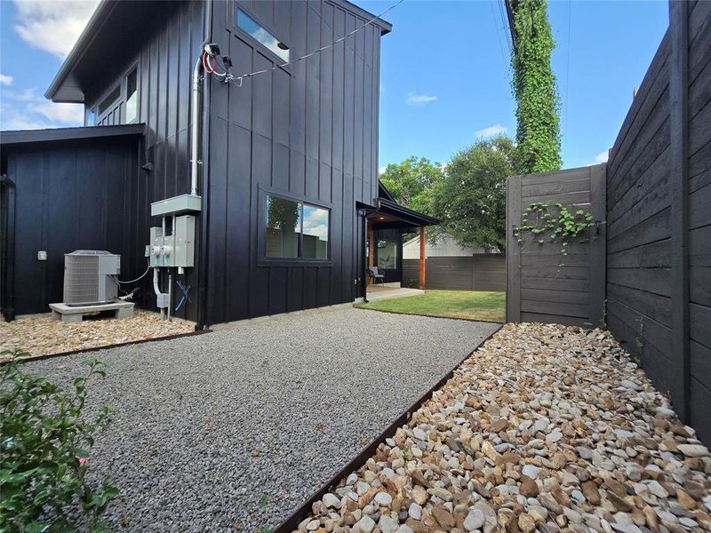 Back yard overview with multiple areas - one half with grass, another part with xeriscape/stone. Add potted plants on top of the metal retaining walls for your custom touch.