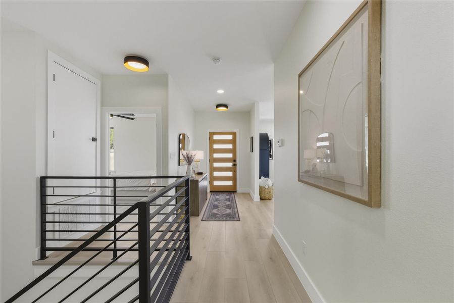 Corridor with light wood-style flooring, an upstairs landing, and recessed lighting