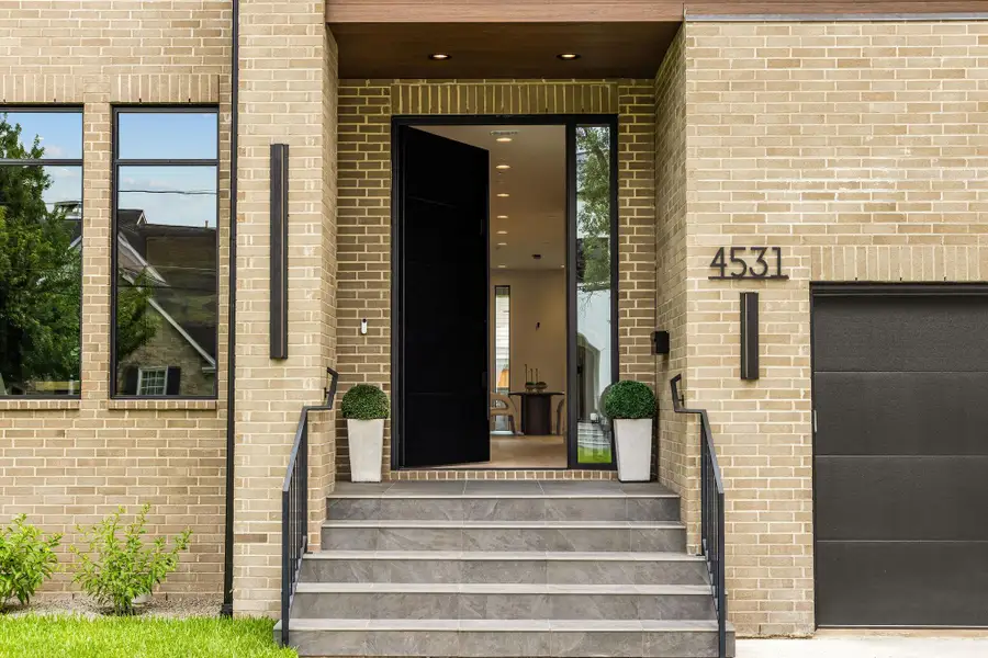 [ENTRANCE] Framed by handsome brickwork, the oversized modern iron door commands attention with its bold dark finish, creating a dramatic yet inviting entrance that defines the home's sophisticated curb appeal.