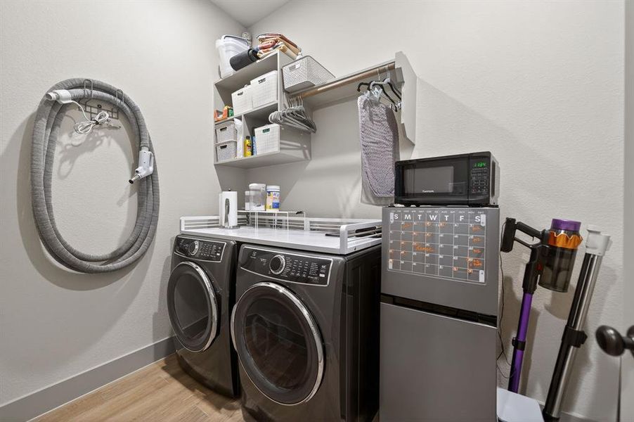 Laundry area with light wood-style flooring and independent washer and dryer Laundry area with light wood-style flooring and independent washer and dryer