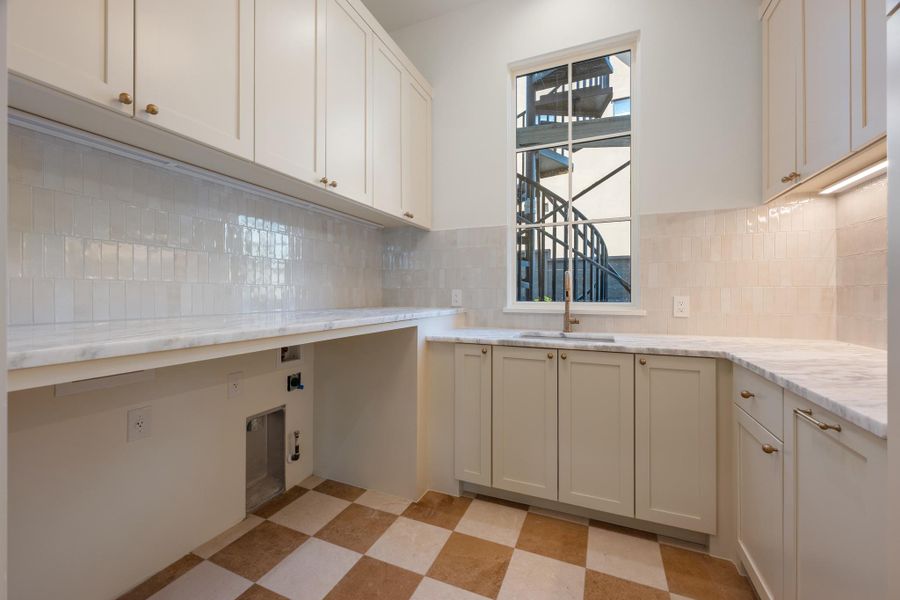 Checkerboard tile flooring and stone countertops anchor this functional space complete with custom cabinetry.